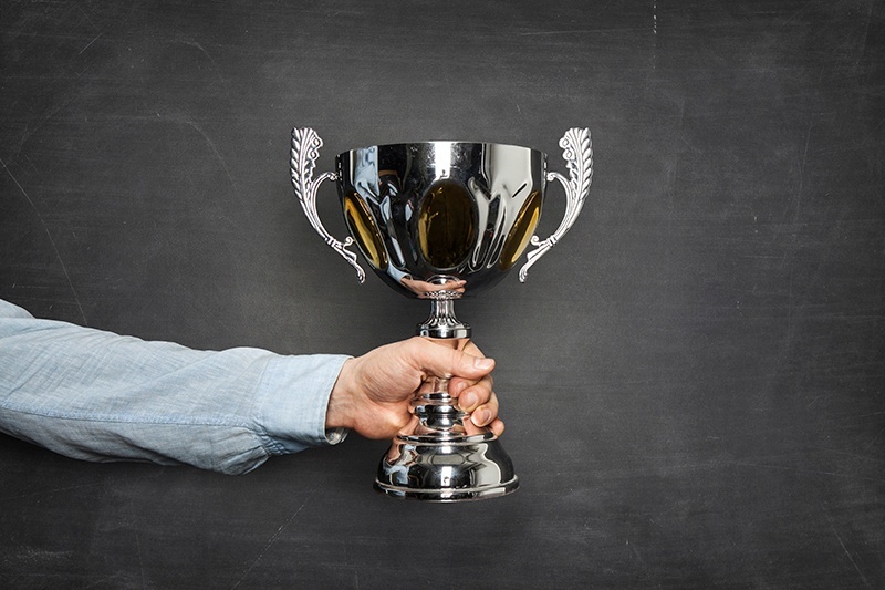 award-man-holding-trophy-against-chalkboard-web.jpg