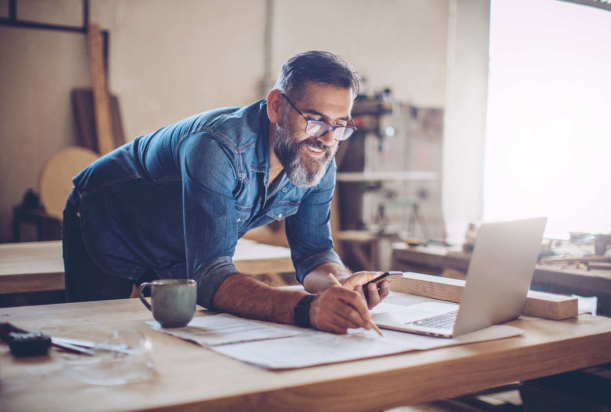 man-designer-pencil-mobile-phone-laptop-coffee-studio