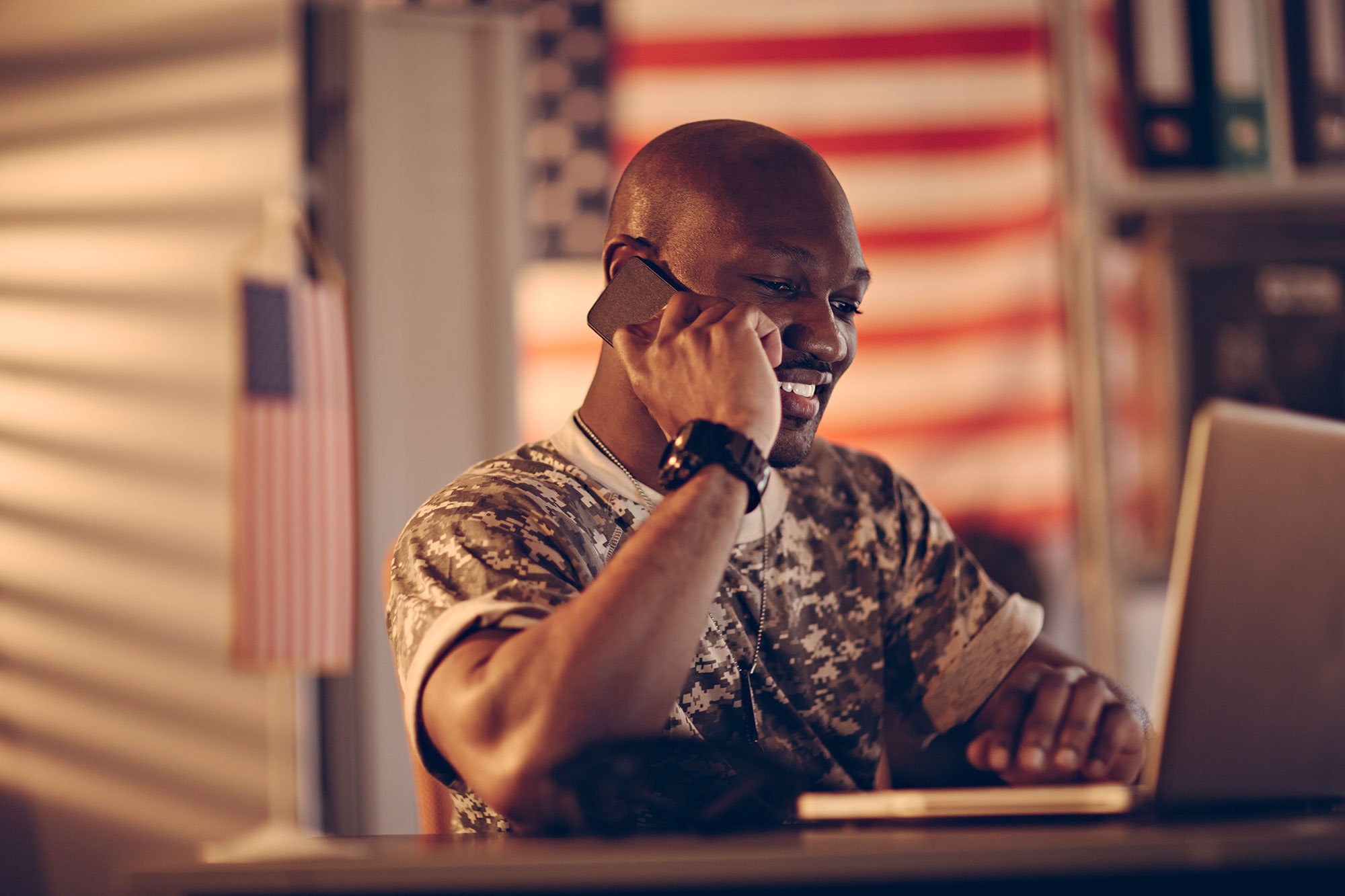 military-man-camoflage-holding-mobile-phone-laptop-american-flag