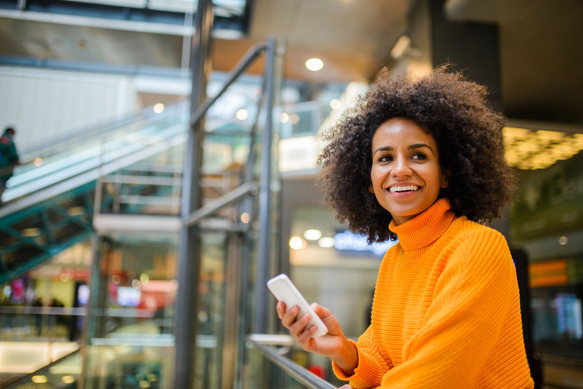 woman-holding-smartphone-in-airport-smiling