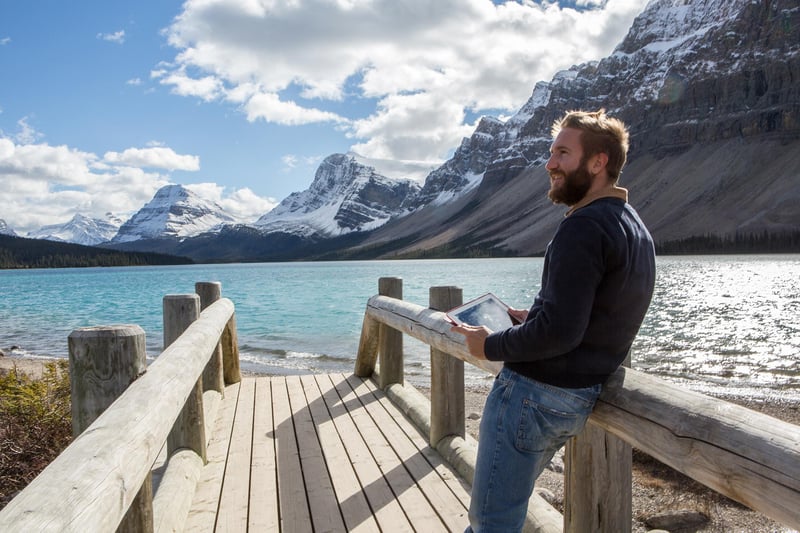 man-holding-tablet-at-lake-with-snowy-mountains.jpg